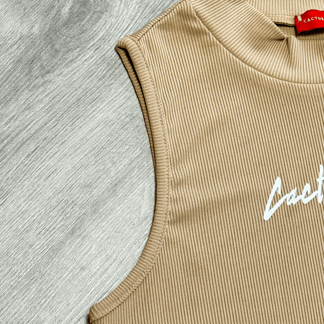 Buttercup Ribbed Crop Top with Cactus Becks logo in white, featuring high neckline and sleeveless design in beige ribbed fabric.