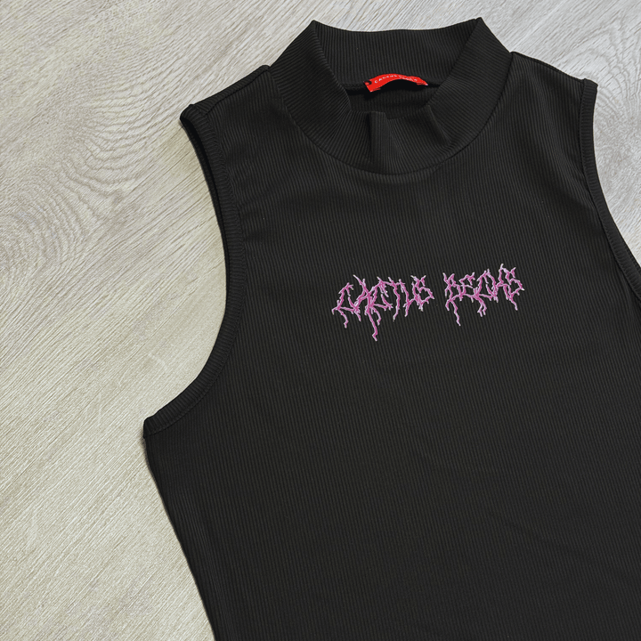 Ribbed sleeveless black crop top with high neckline and pink Cactus Becks logo on gray wooden background.