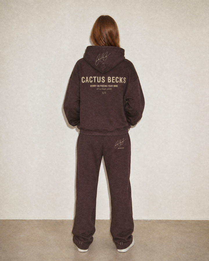 Person wearing a brown 'Cactus Becks' tracksuit against a plain background