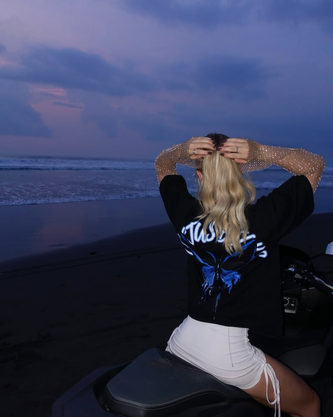 Person sitting on a motorcycle at sunset on a beach