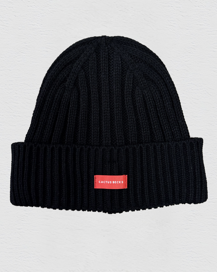 Black beanie with a red label on a light gray background