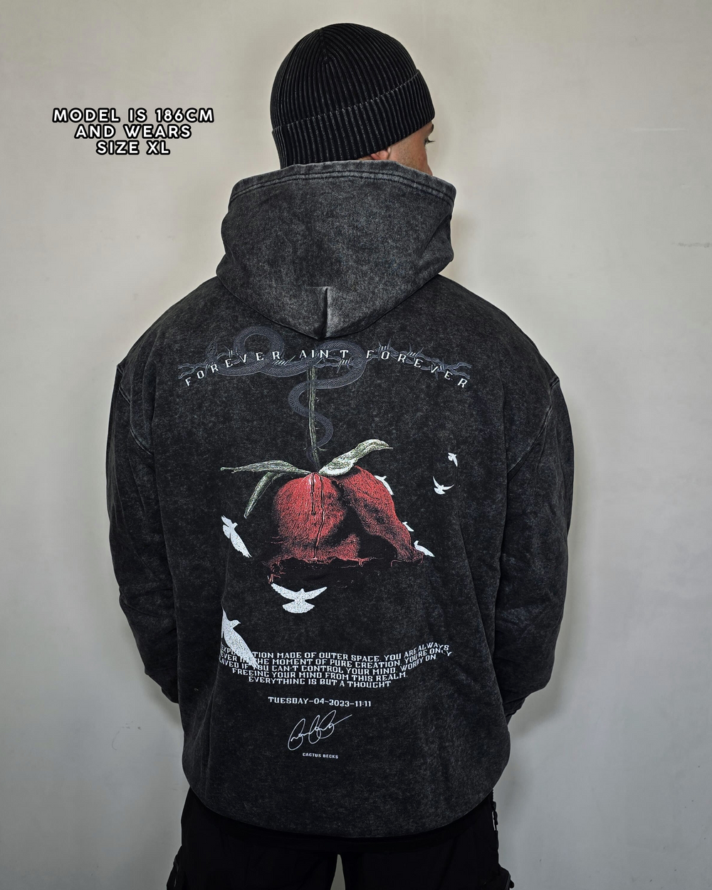 Person wearing a dark gray hoodie with a graphic design on the back against a plain background