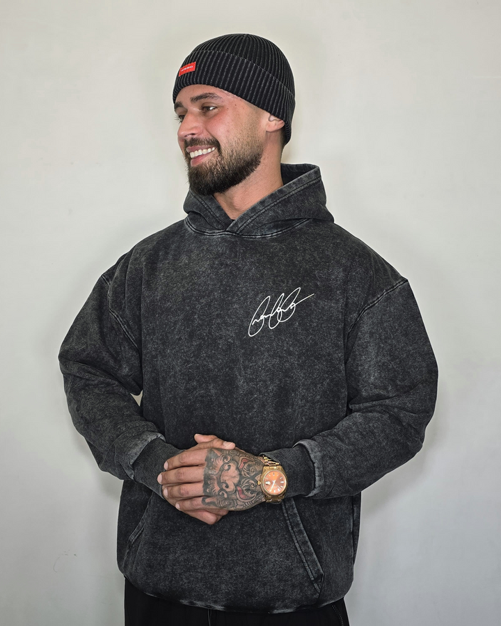 Man wearing a black hoodie with a logo and a beanie against a white background