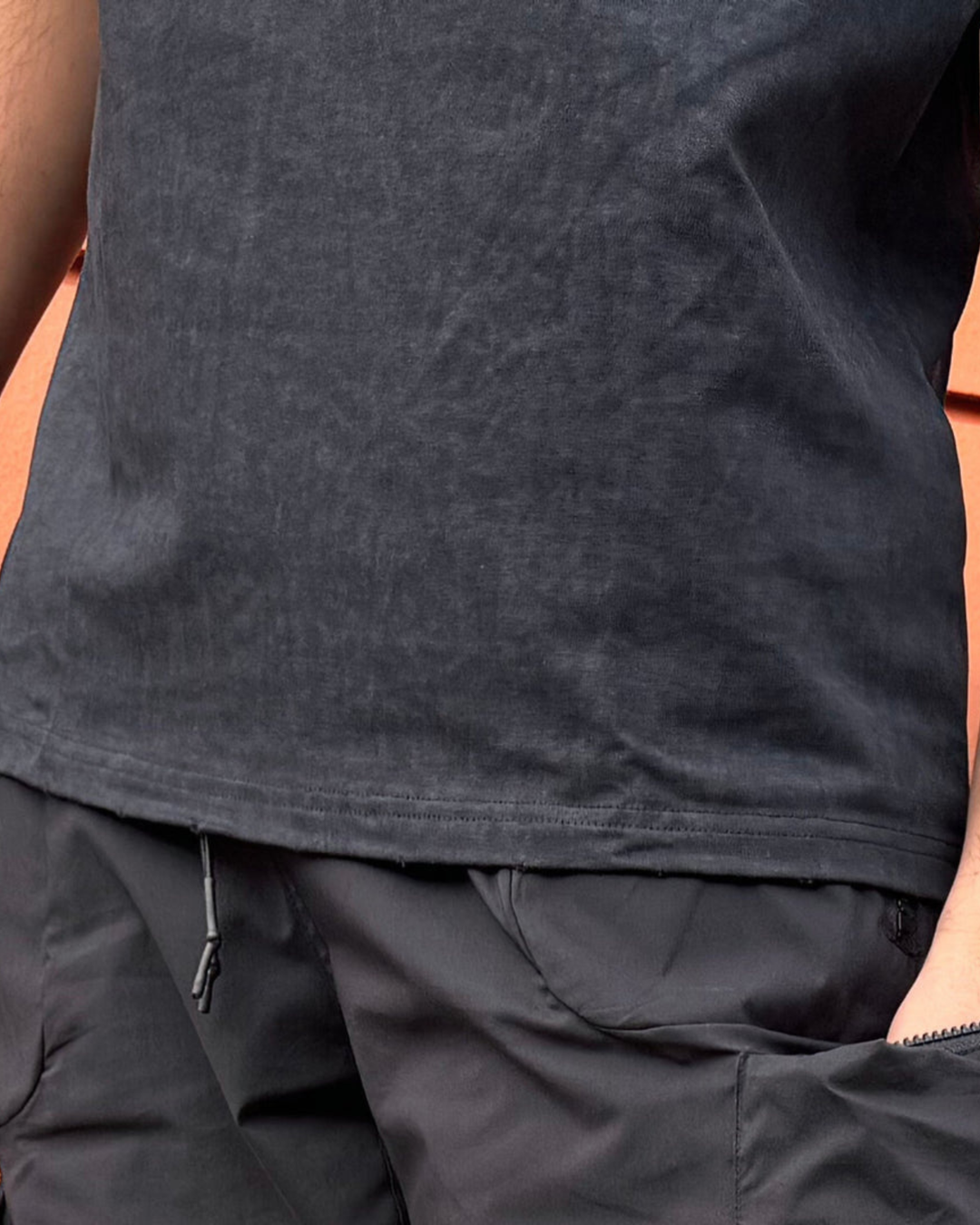 Close-up of a person wearing a dark gray sleeveless shirt and pants.