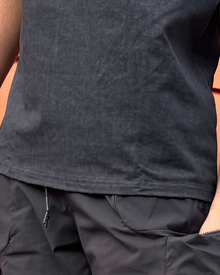 Close-up of a person wearing a dark gray sleeveless shirt and pants.