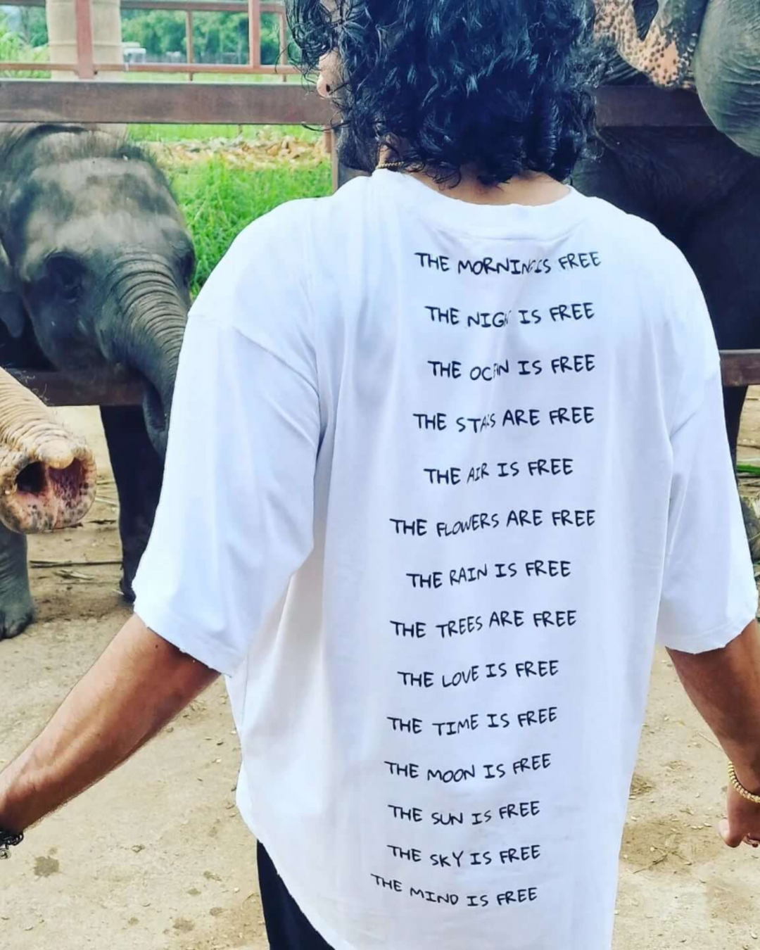 Person wearing a white t-shirt with text in front of elephants
