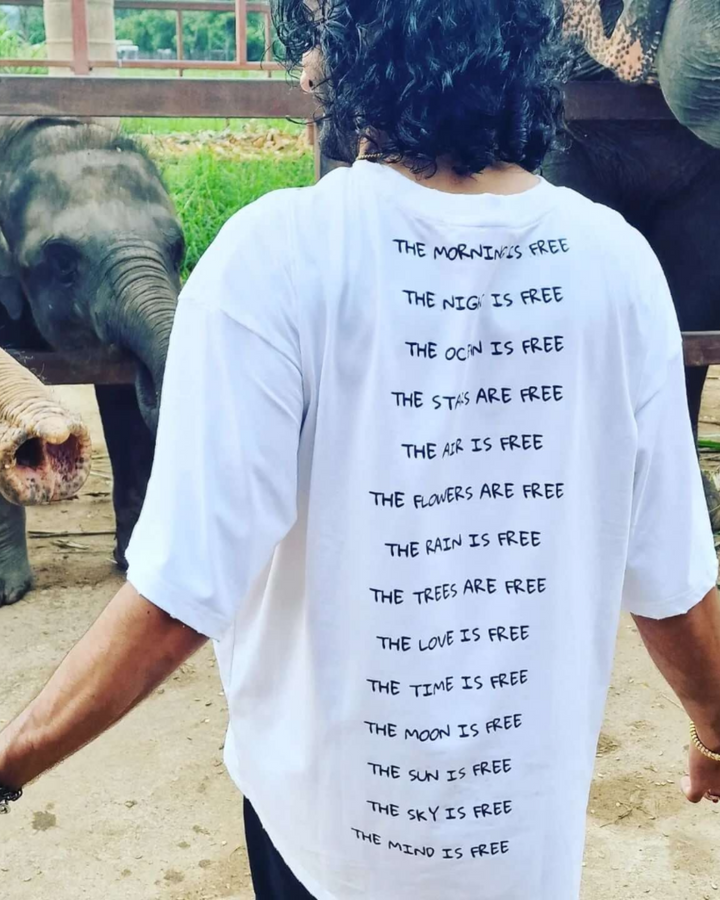Person wearing a white t-shirt with text in front of elephants