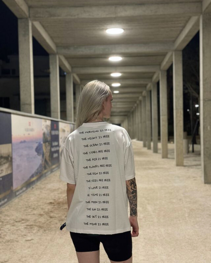 Person wearing a white t-shirt with text on the back in an outdoor setting at night.