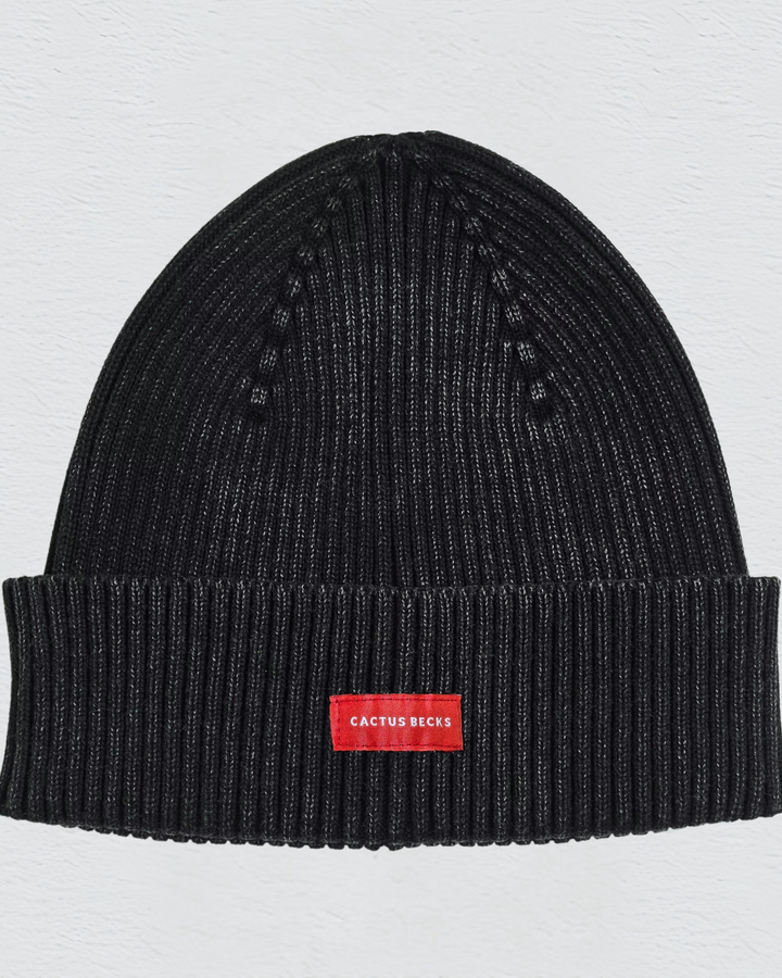 Black beanie with a red label on a light gray background